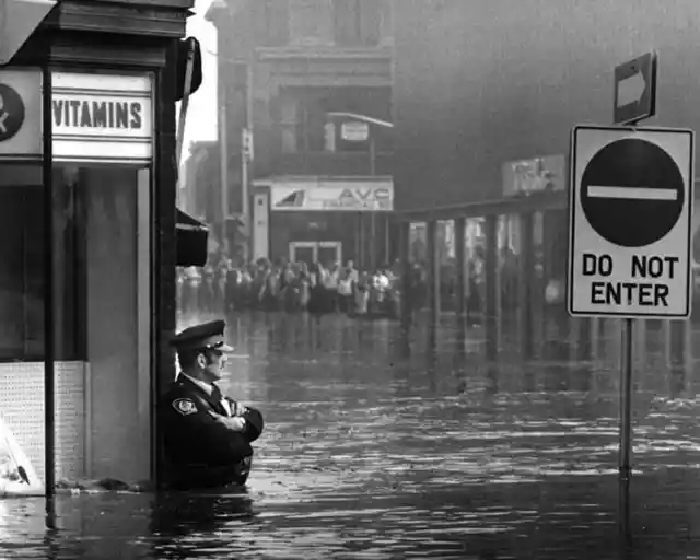 Police Officer Guarding A Pharmacy During A Flood